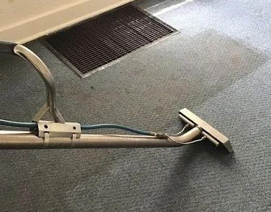 Carpet extraction wand beside a floor vent